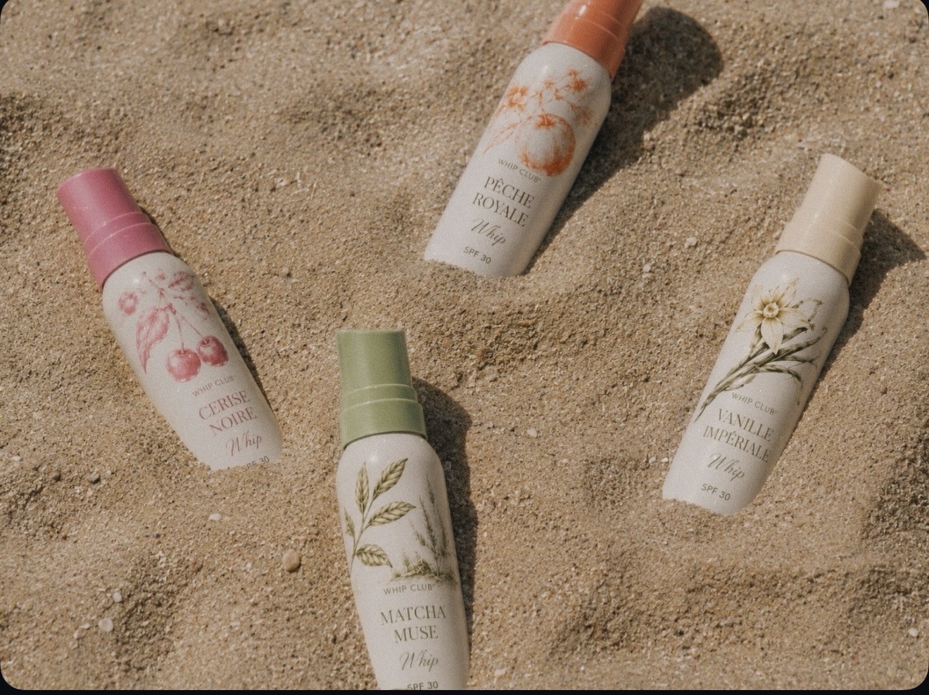 Whip Club bottles resting in warm sand